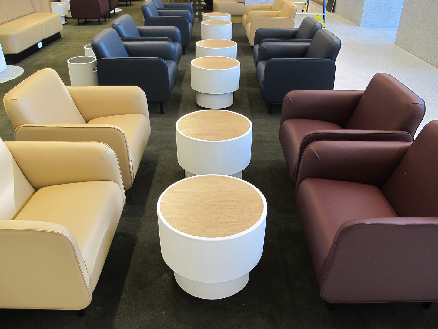Contemporary seating area with beige, blue, and brown chairs and white concrete cylindrical tables.